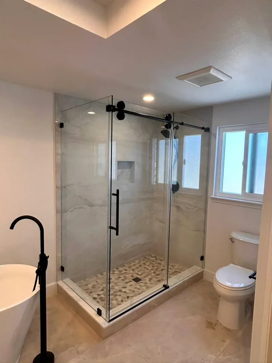Customized sliding shower door with fixed glass panel and matte black hardware installed in Los Angeles