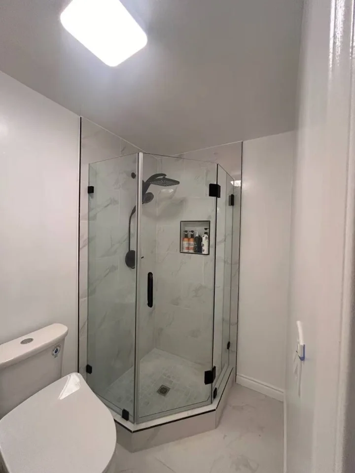 Custom neo-angle frameless shower enclosure with matte black hardware installed in Los Angeles California